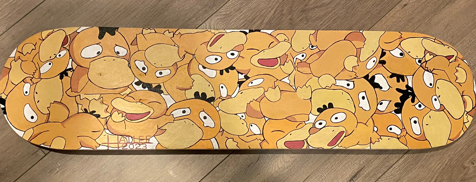  a skateboard baseplate entirely covered with paintings of Phsyduck from pokemon.